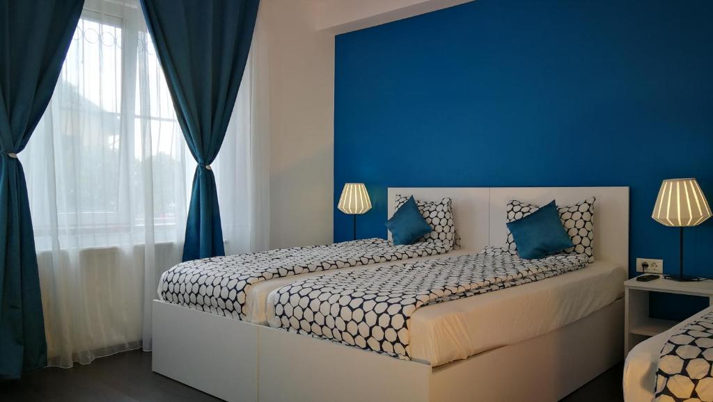 una camera da letto con pareti blu e un letto con cuscini blu di Coroni Residence a Braşov