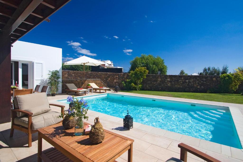 una piscina en un patio trasero con mesa y sillas en Coral Villas, en Puerto del Carmen
