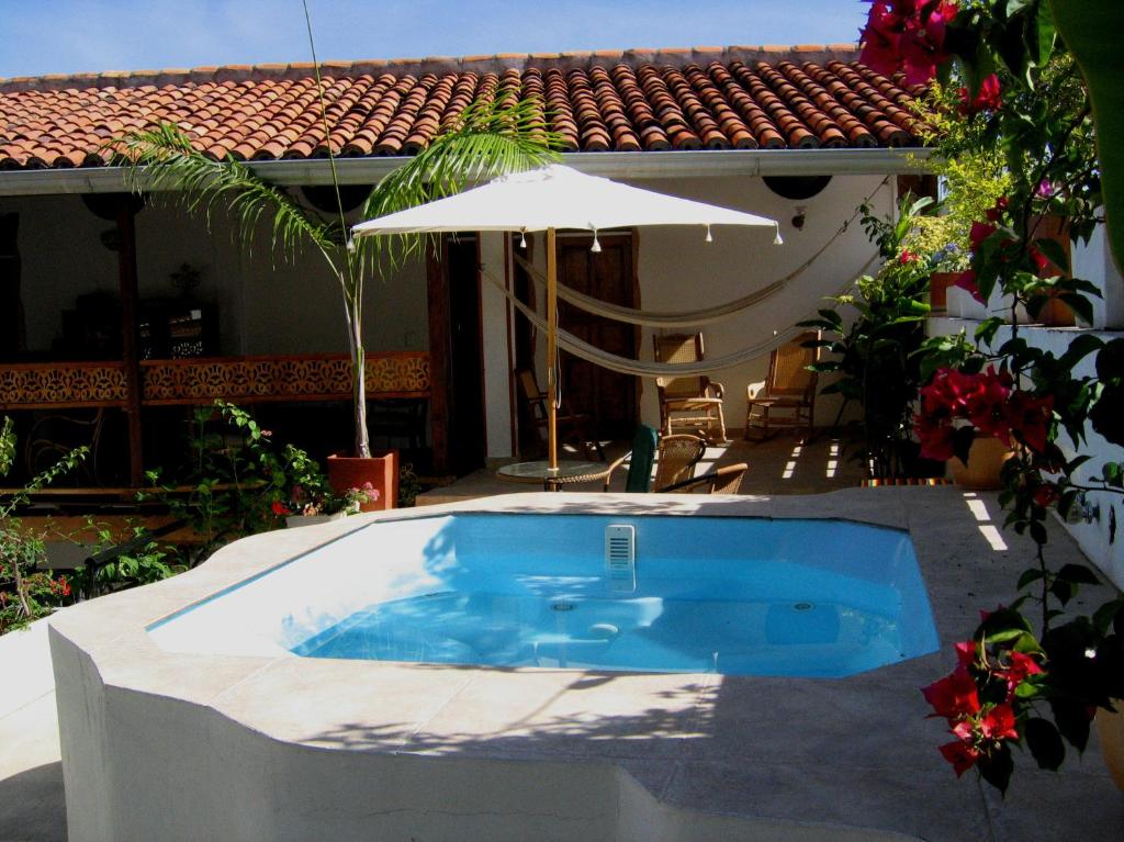 una piscina con sombrilla junto a una casa en Hotel Casa Belle Epoque, en Honda