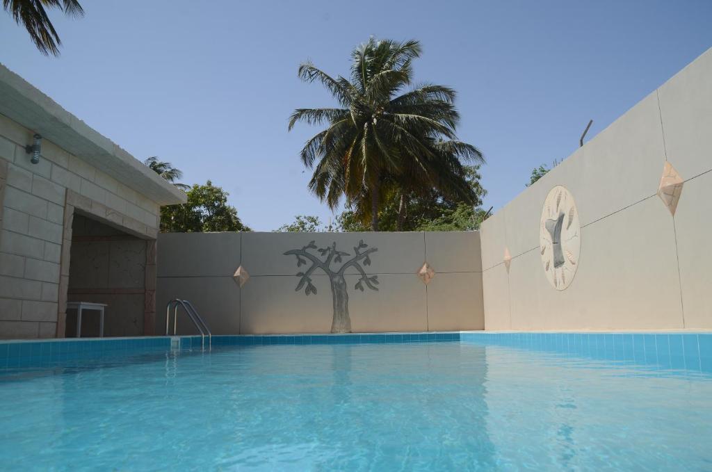 a swimming pool with a palm tree in the background at Hotel La Perle in Saint-Louis
