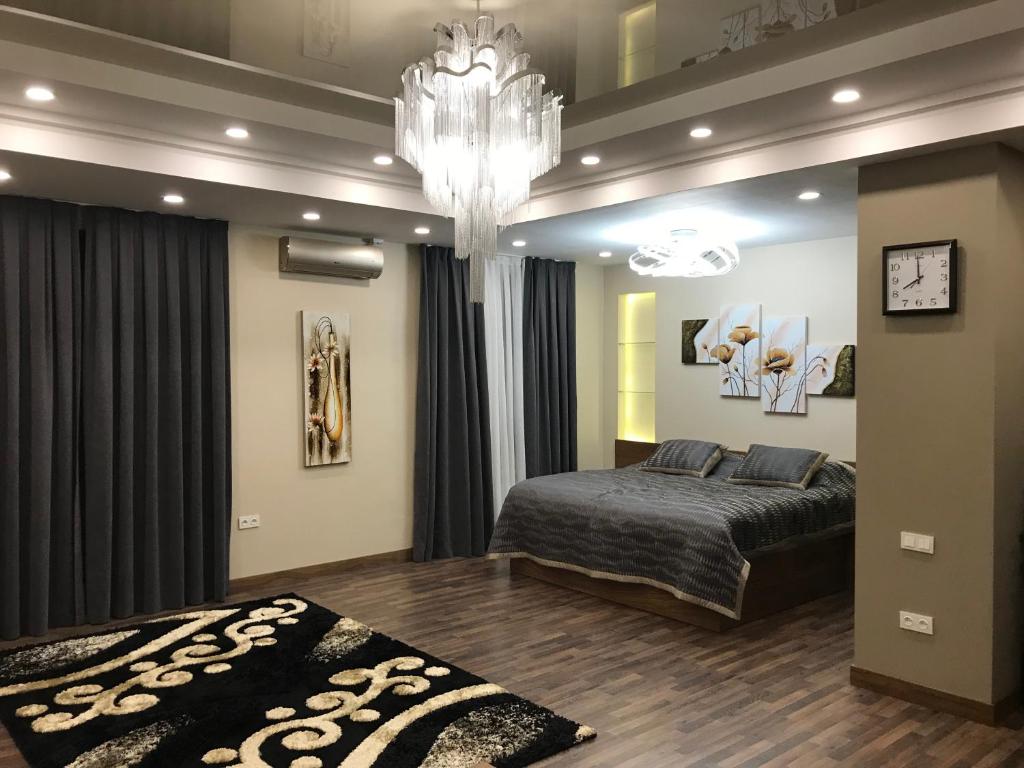 a bedroom with a large bed and a chandelier at Green City Apartment 1 in Tashkent