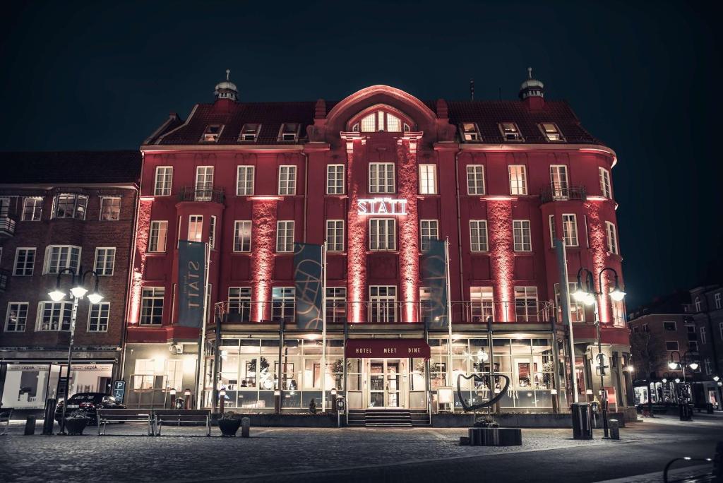 Un grand bâtiment rouge avec des lumières allumées la nuit dans l'établissement Statt Hassleholm BW Signature Collection, à Hässleholm