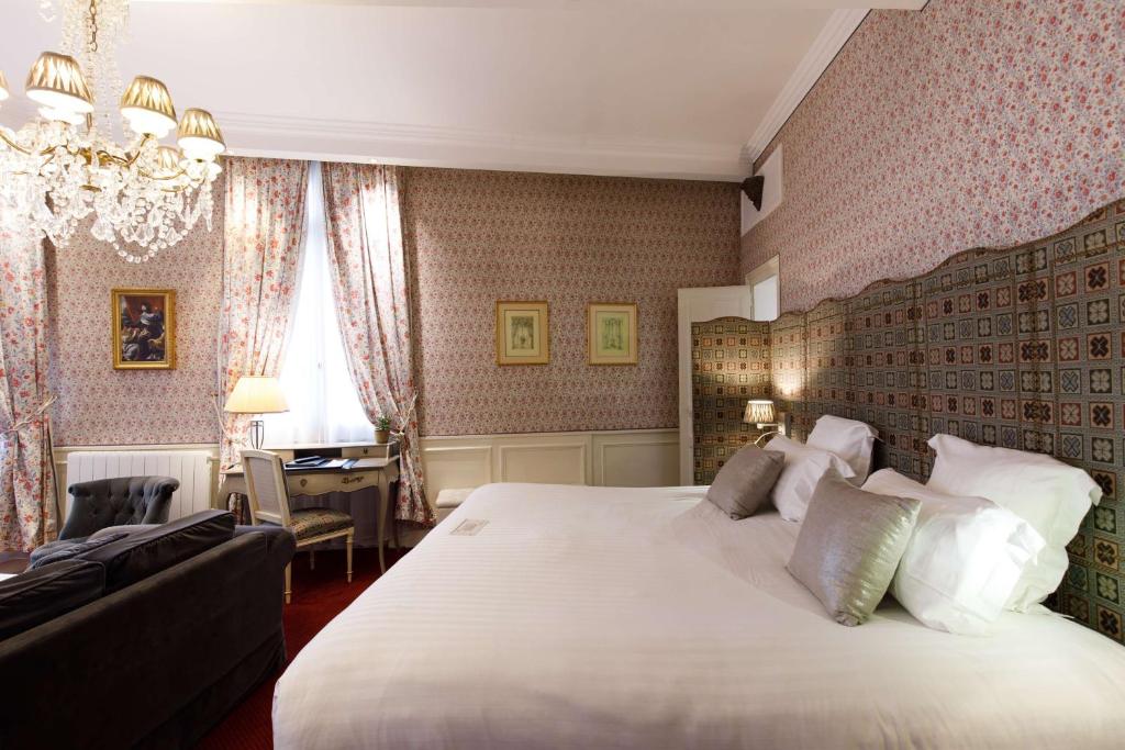 Hotel & Spa Le Grand Monarque, BW Premier Collection في شارتر: غرفة نوم مع سرير أبيض كبير ومكتب
