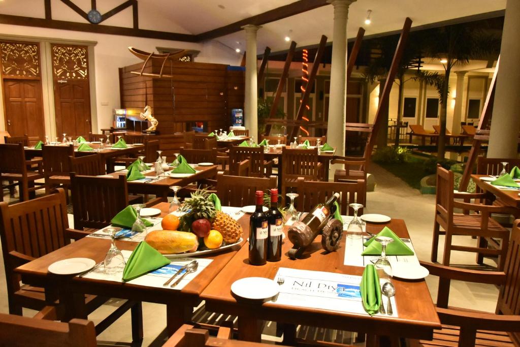 un restaurante con mesas de madera y fruta. en Nil Diya Beach Resort en Matara