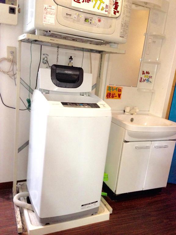 a kitchen with a microwave on top of a refrigerator at Little Asia Guest House in Naha