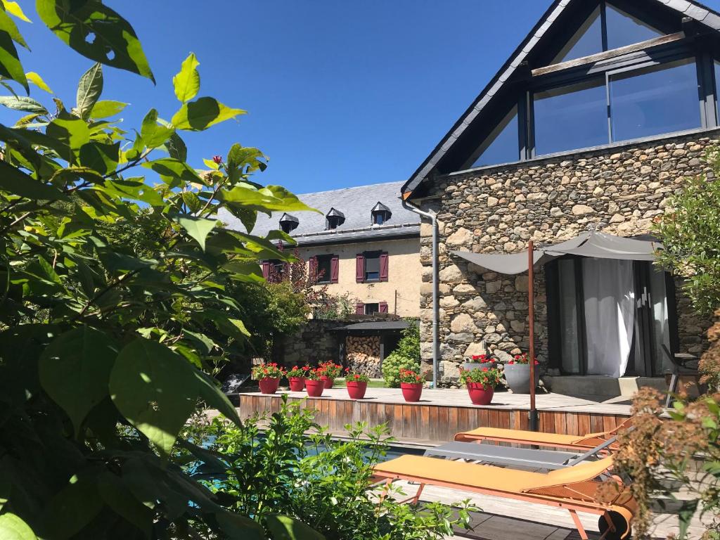 una casa con terraza con plantas y sombrilla en Maison Eth Bordac & Bordac Petit, en Cazeaux-de-Larboust
