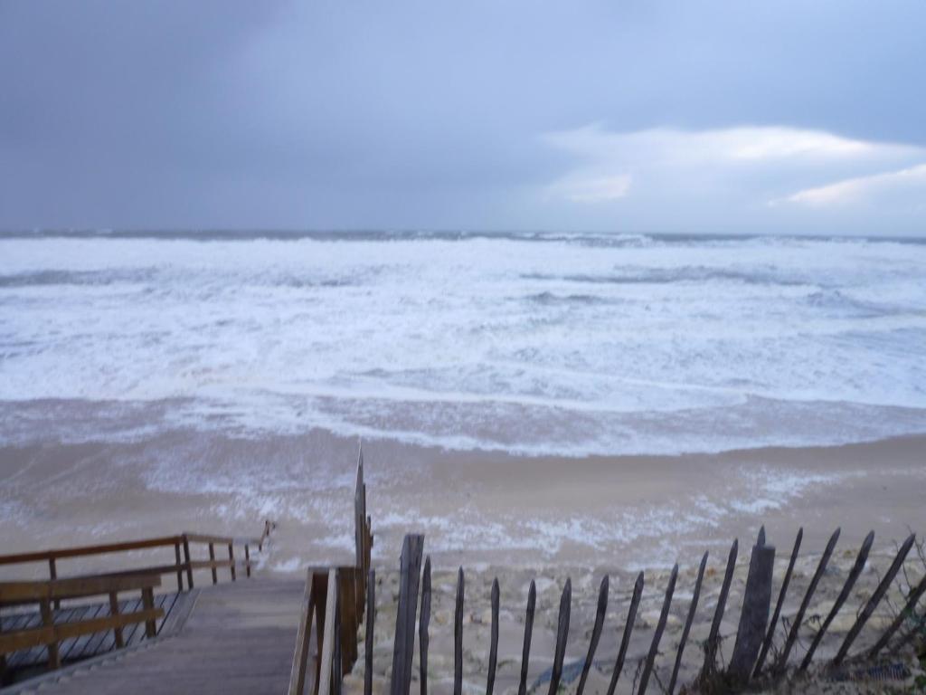 a view of the ocean from a beach with a fence at 18 Résidence Parc de la Dune in Lacanau