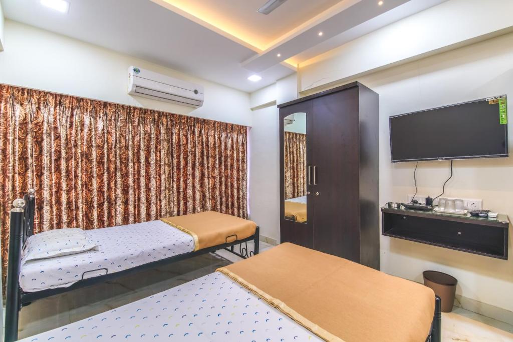 a room with two beds and a flat screen tv at Nest Dormitory in Mumbai