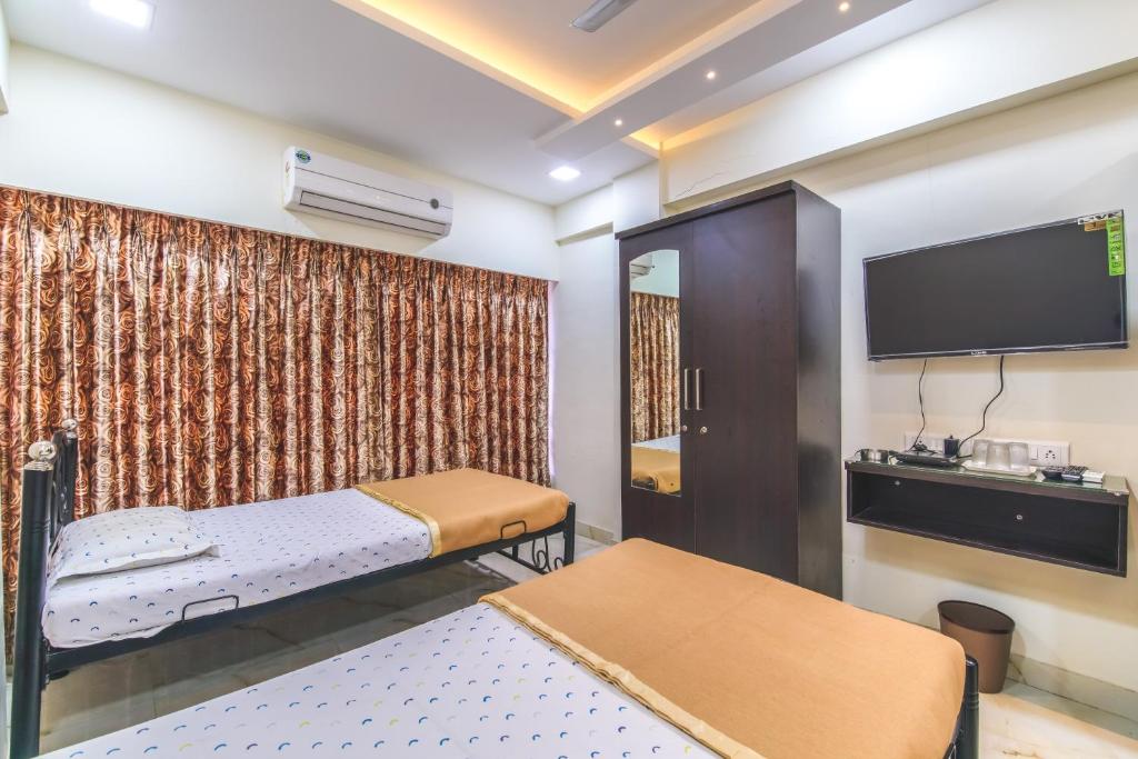 een kamer met 2 bedden en een flatscreen-tv bij Vnest Dormitory in Mumbai