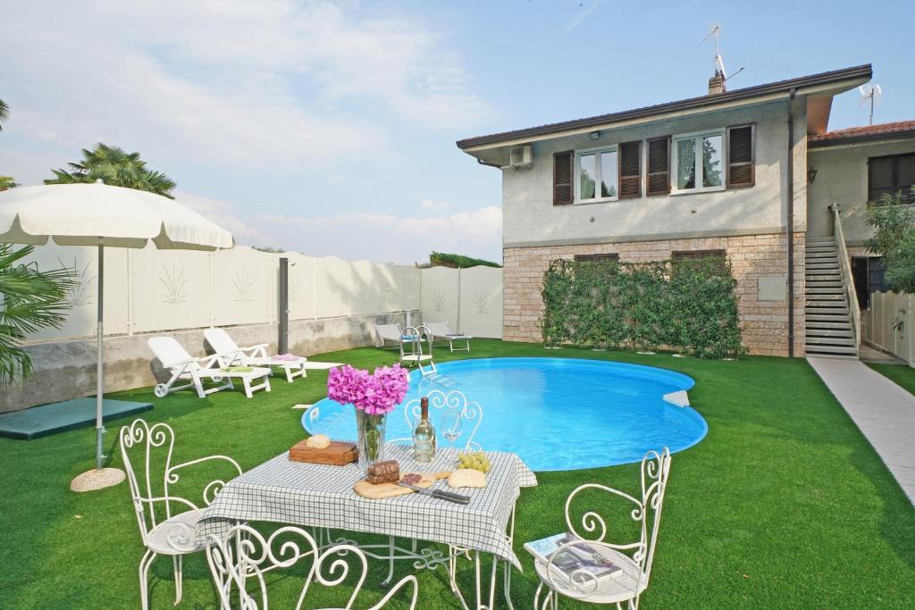 a backyard with a small pool and a table with flowers at Appartamento Jessica con piscina privata in Manerba del Garda