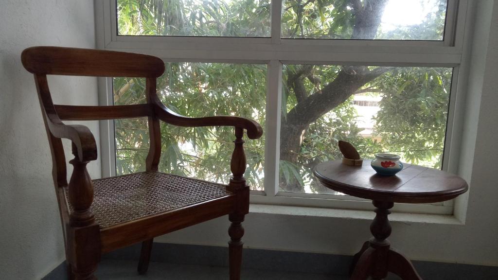 a wooden chair sitting in front of a window at Adams Wood House Ayurveda Homestay Kochi in Cochin