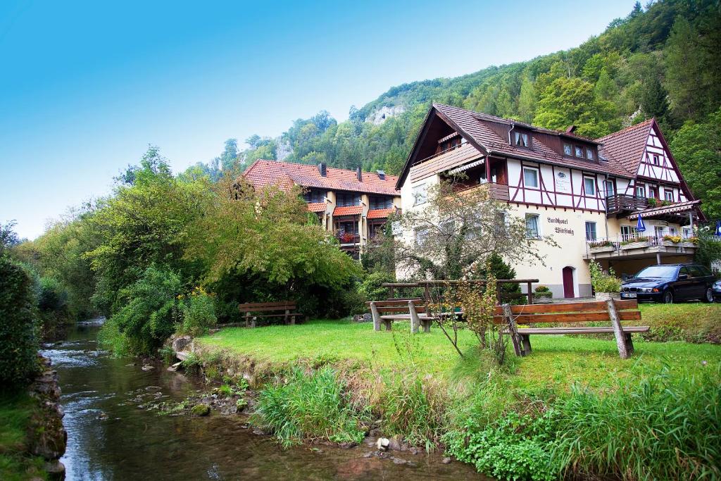 a house sitting next to a river next to a building at Landhotel Gasthof Wittstaig in Gundelfingen