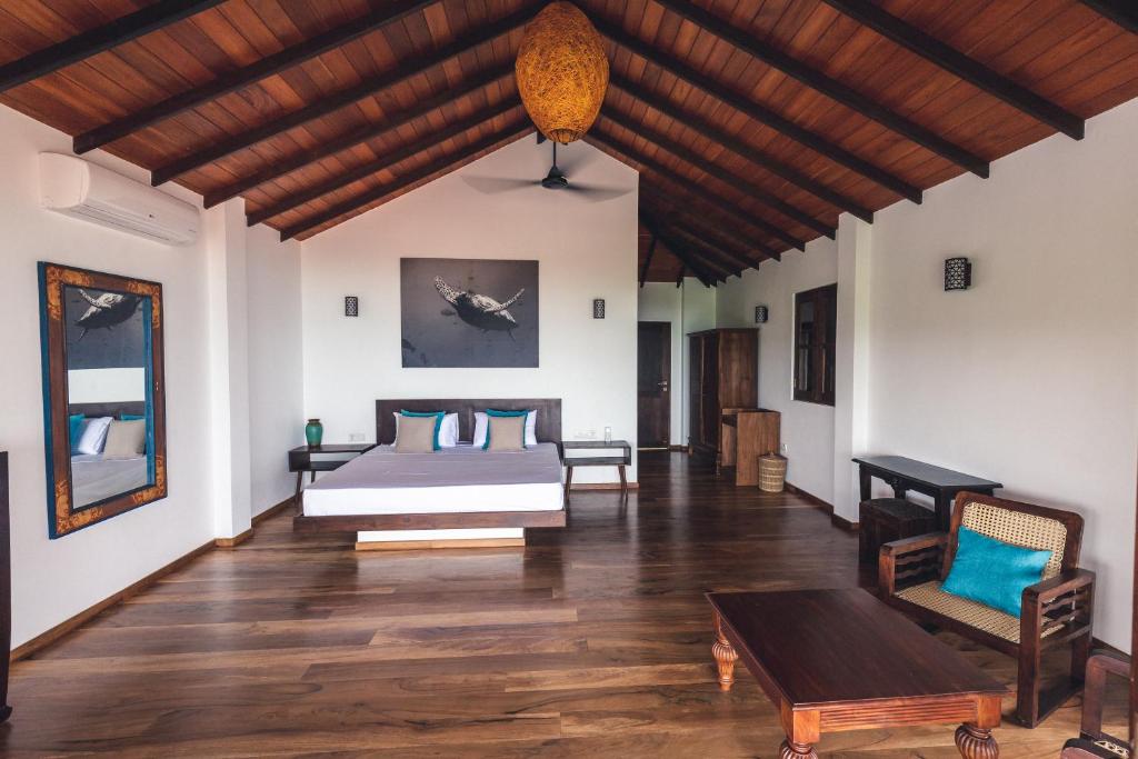 una camera da letto con un letto e un pavimento in legno di OMIA a Tangalle