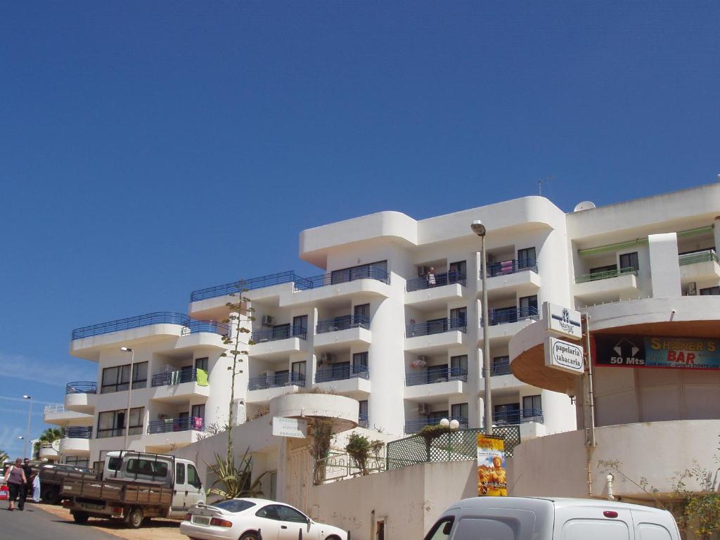 a white building with cars parked in front of it at Naturmar Praia in Albufeira