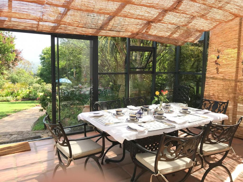 comedor con mesa, sillas y ventanas en Klein Bosheuwel Guest House, en Ciudad del Cabo