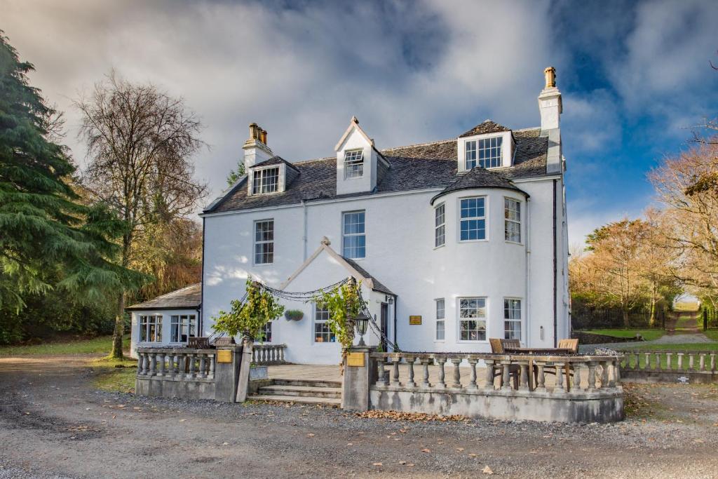 una casa blanca con una valla delante en Greshornish House Hotel, en Edinbain