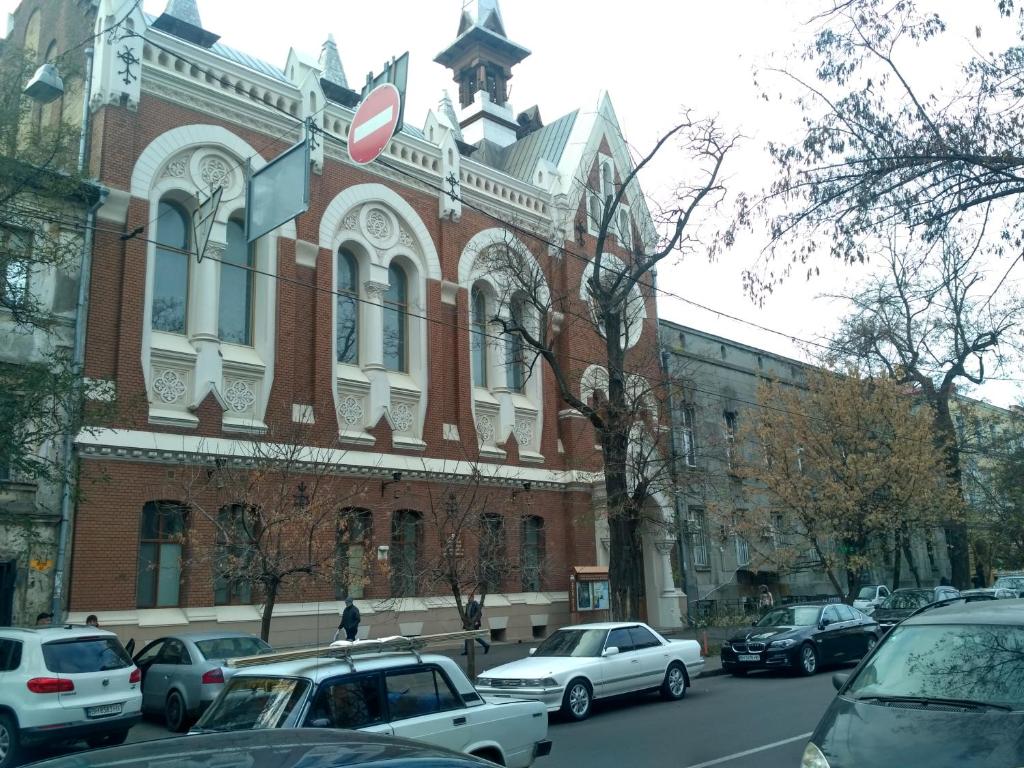 een groot bakstenen gebouw met auto's geparkeerd voor het bij Gorsad Apartment in Odessa