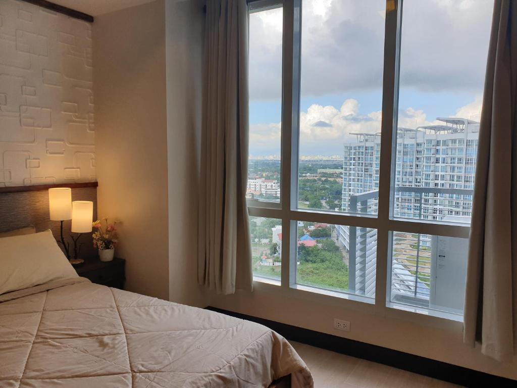 ein Schlafzimmer mit einem Bett und einem großen Fenster in der Unterkunft One Pacific Residence Condominium Tower C-16N in Mactan