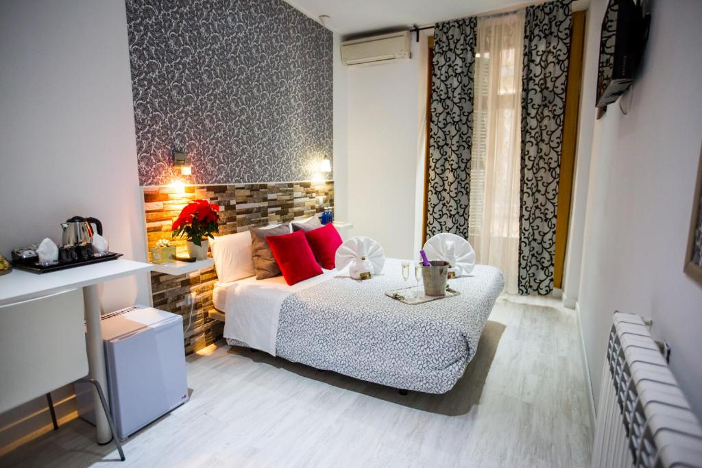 Un dormitorio con una cama con almohadas rojas y una mesa. en Hostal Adis en Madrid
