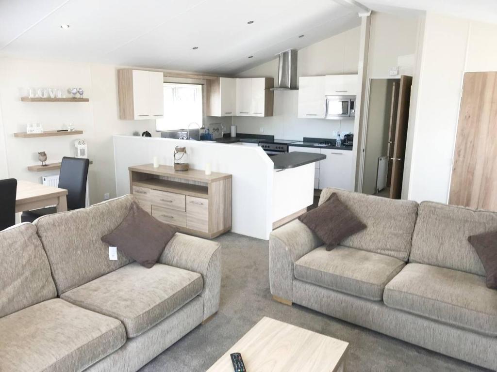 a living room with two couches and a kitchen at Mikanda Lodge in Clacton-on-Sea
