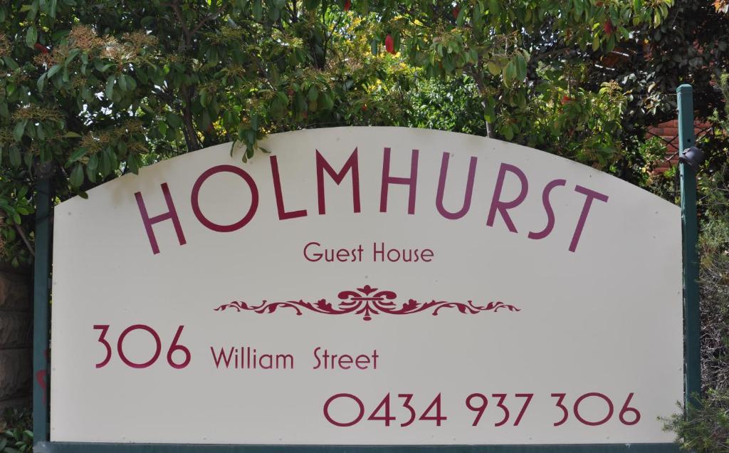 a sign for a hommit guest house in front of a tree at Holmhurst Guest House in Bathurst