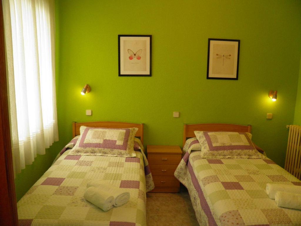 two beds in a room with green walls at Hostal Angelines in Madrid