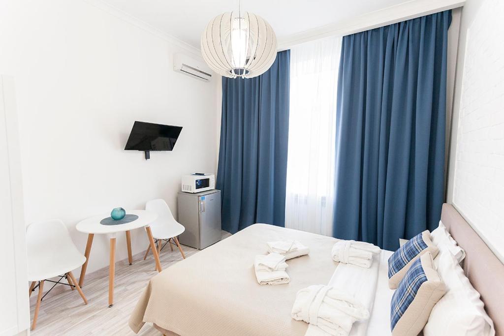 1 dormitorio con 1 cama con cortinas azules y mesa en Kharkov & Apartments in the city center, en Járkov