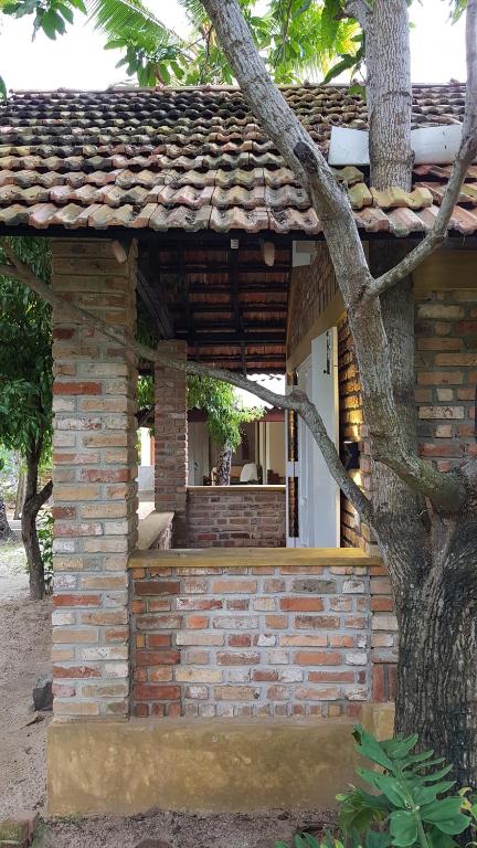 een bakstenen gebouw met een boom ervoor bij Roseberry Cottage in Negombo