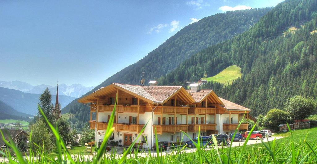 a large wooden building with mountains in the background at Hotel Gsieserhof in Valle Di Casies