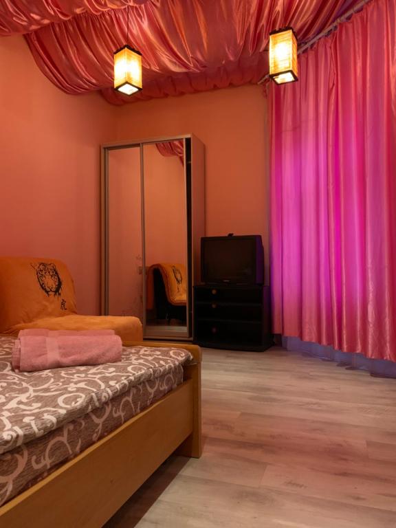 una camera con tende rosa, un letto e una TV di 5Kotliarska Moisha House a Lviv
