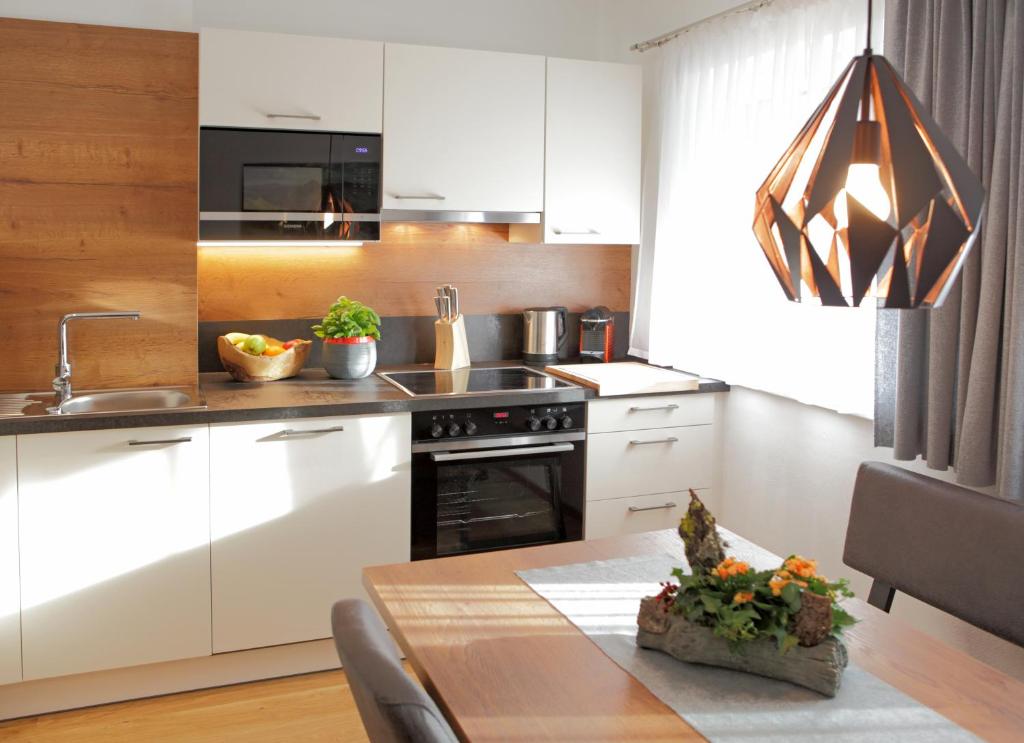 cocina con armarios blancos y mesa de madera en Appartementhaus Reiter Village Room, en Altenmarkt im Pongau