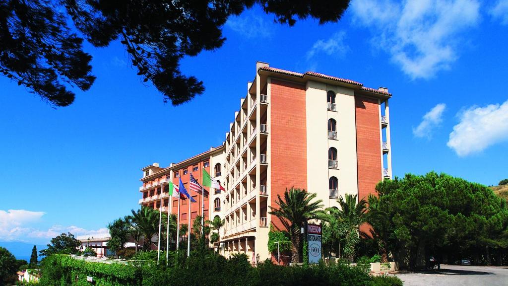 un edificio rojo y blanco con árboles delante de él en 501 Hotel, en Vibo Valentia