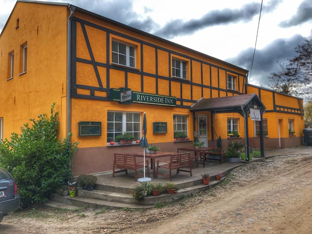 ein Gebäude mit Bänken und Tischen davor in der Unterkunft Riverside Inn in Oderberg