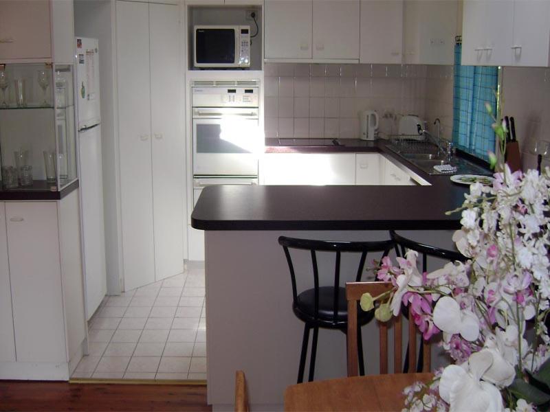 een keuken met witte kasten en een zwart aanrecht bij Accommodation Sydney North - Forestville 4 bedroom 2 bathroom house in Forestville