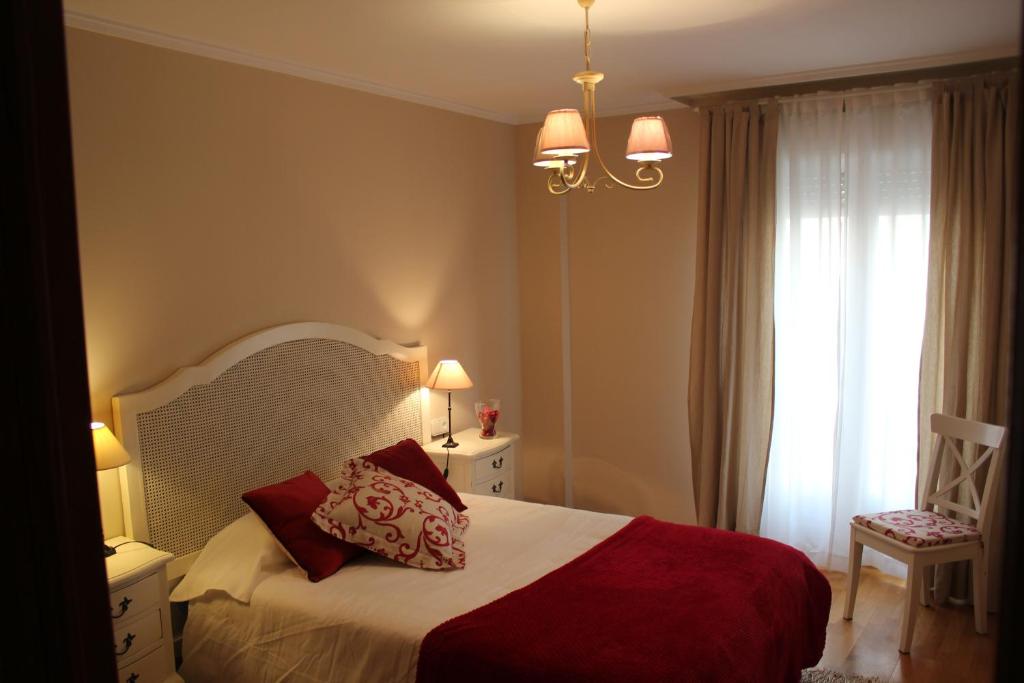 a bedroom with a bed with a red blanket and a window at El Collado 17 in Soria