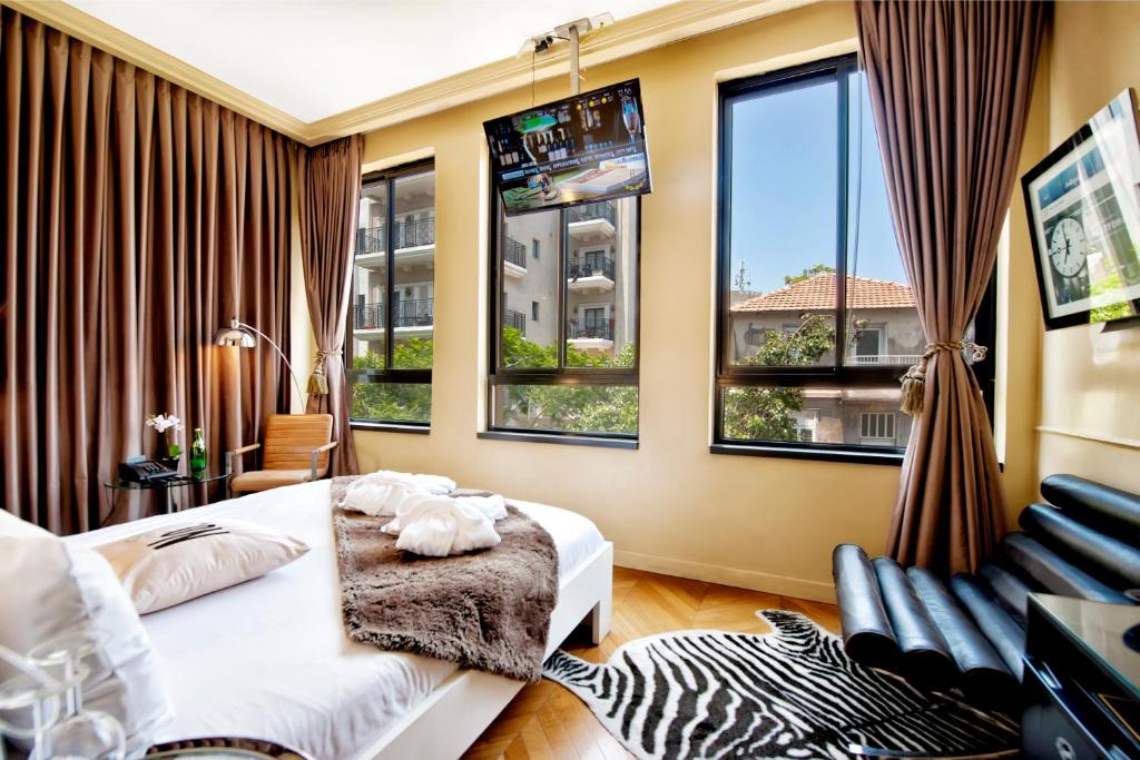 a bedroom with a bed and a chair and windows at Montefiore 16 - Urban Boutique Hotel in Tel Aviv