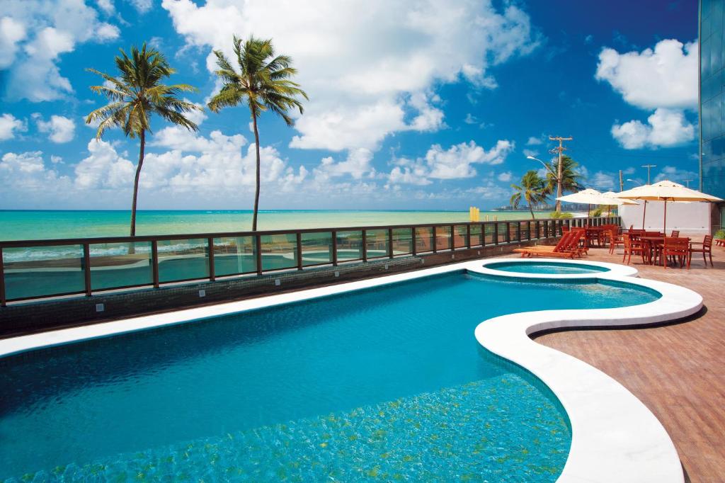 a swimming pool with a view of the beach at Ritz Suites Home Service in Maceió