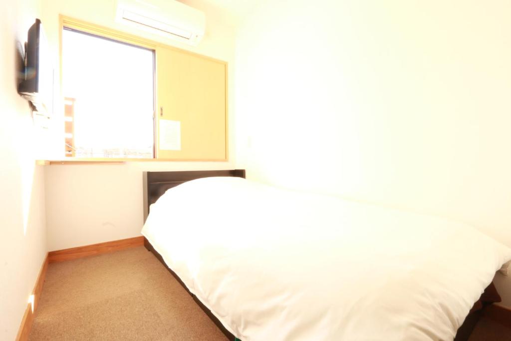 a bedroom with a bed and a window at Simple Sleep 個室カプセル in Hitoyoshi