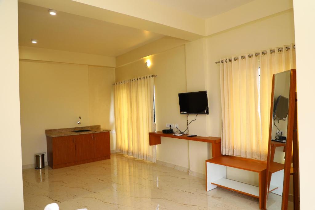 a living room with a flat screen tv and a television at Lali Petals in Madikeri