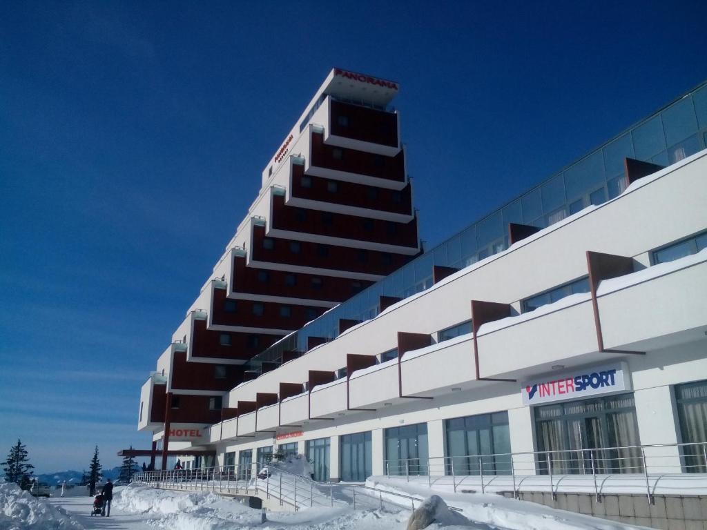 Un gran edificio con nieve delante. en Panorama Apartmany, en Štrbské Pleso