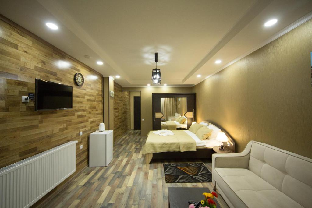 a bedroom with a bed and a tv and a couch at Hotel Dimasi in Kutaisi