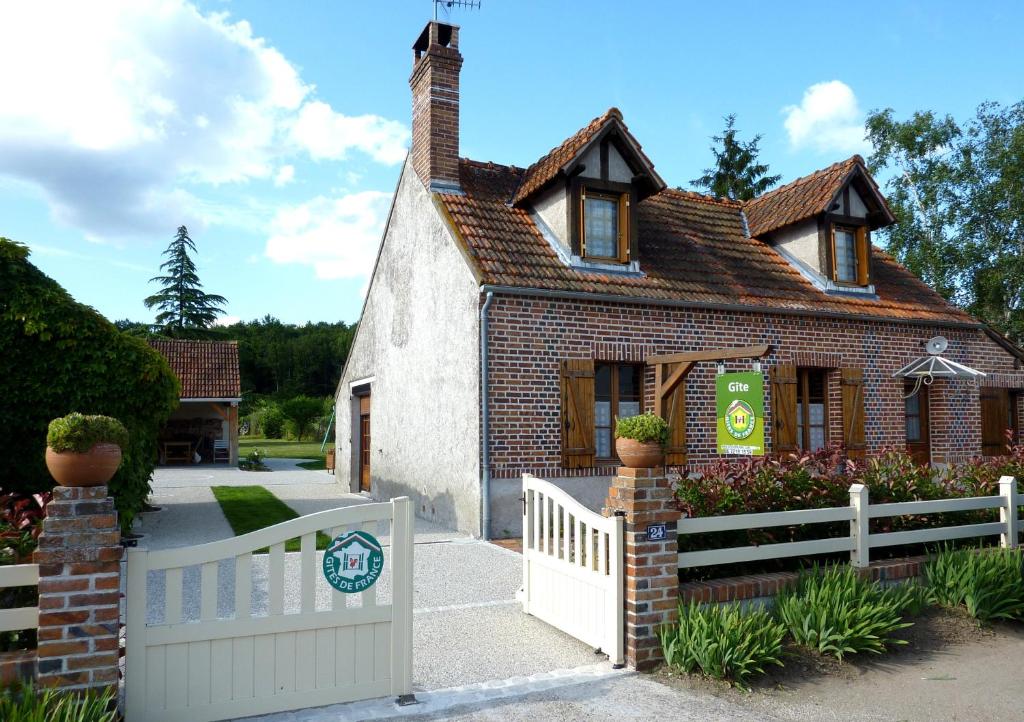 a small brick house with a white fence at Gite de Sologne "les galoches" in Dhuizon