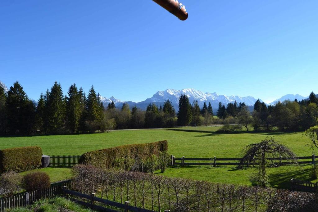 a green field with hay bales and a fence at Alpenwohnung Neuner in Wallgau