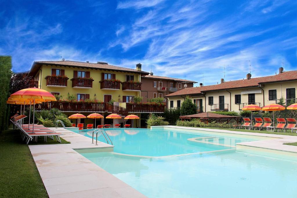 a swimming pool in front of a hotel with umbrellas at Hotel Romantic in Cavaion Veronese