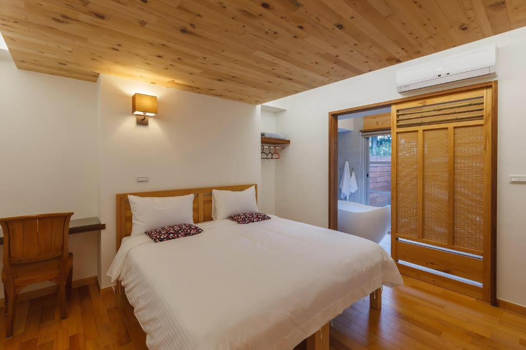 um quarto com uma cama branca e um tecto de madeira em Hou Shan Ren Jia B&B Hall A em Yung-an-ts'un