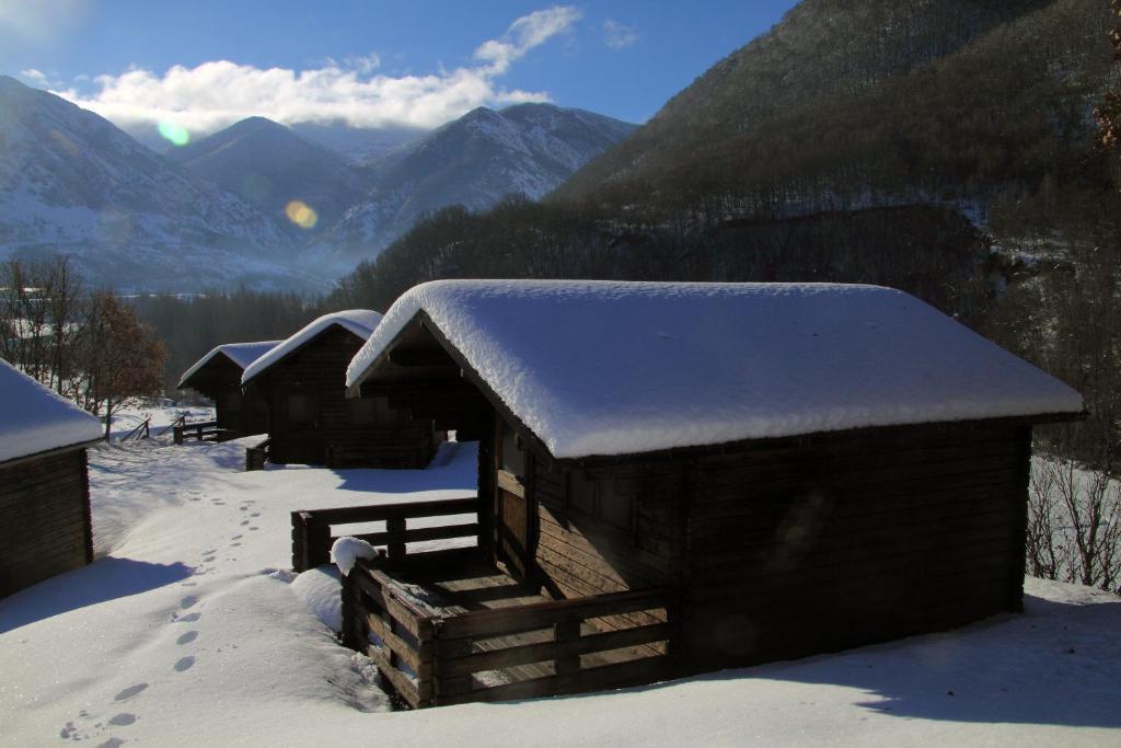 um edifício coberto de neve com montanhas ao fundo em Camping Laciana Natura em Villablino