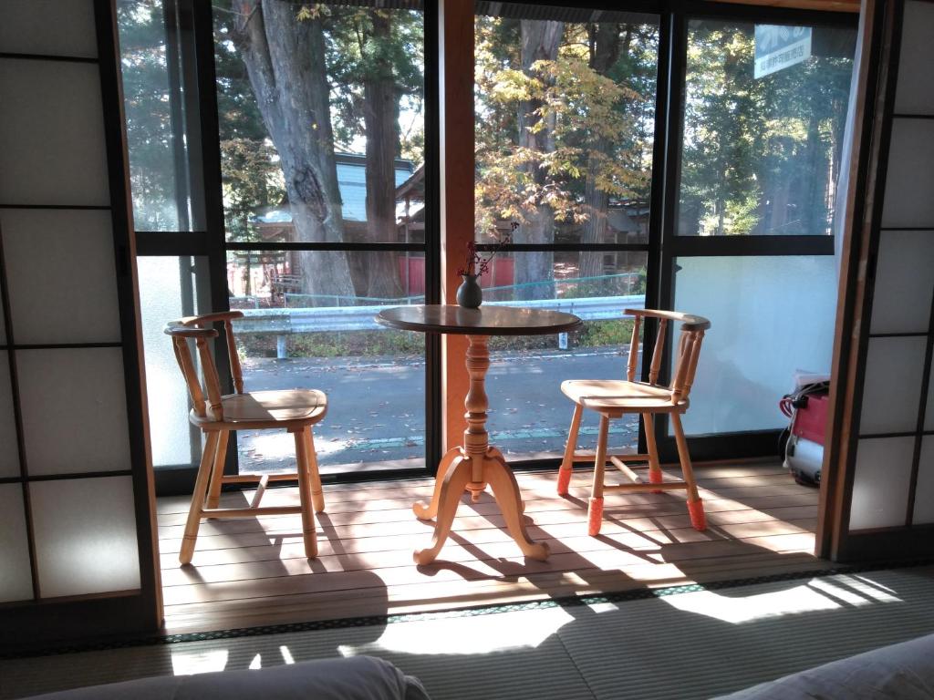a table and two chairs on a screened in porch at Minpaku Sarai Nikkoya in Okkia