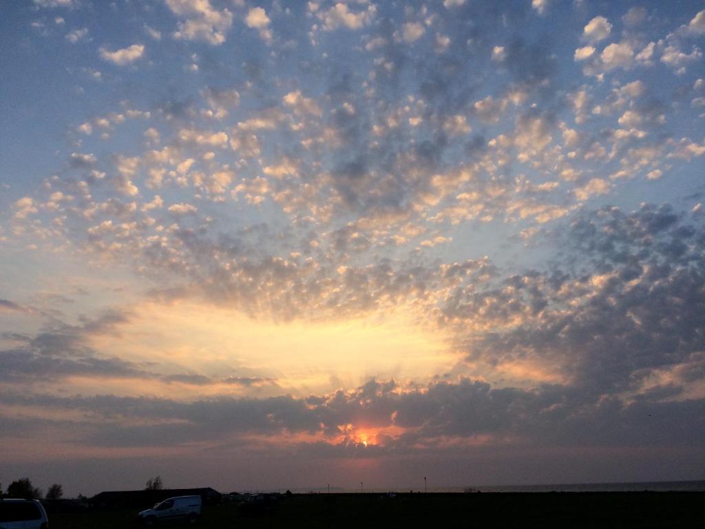 a cloudy sky at sunset with a van in a field at Passengers House in Whitstable