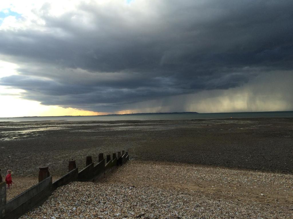 a person walking on the beach with a storm approaching at Passengers House in Whitstable