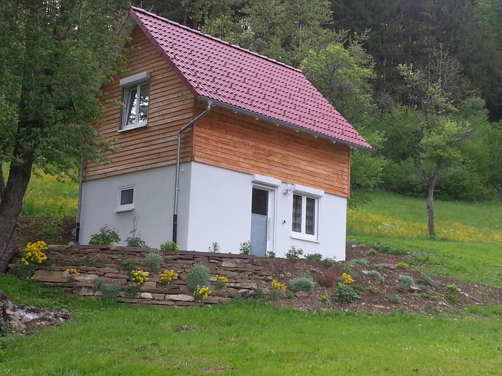 una pequeña casa con una pared de piedra en un patio en Ferienhaus Quelle, en Loßburg